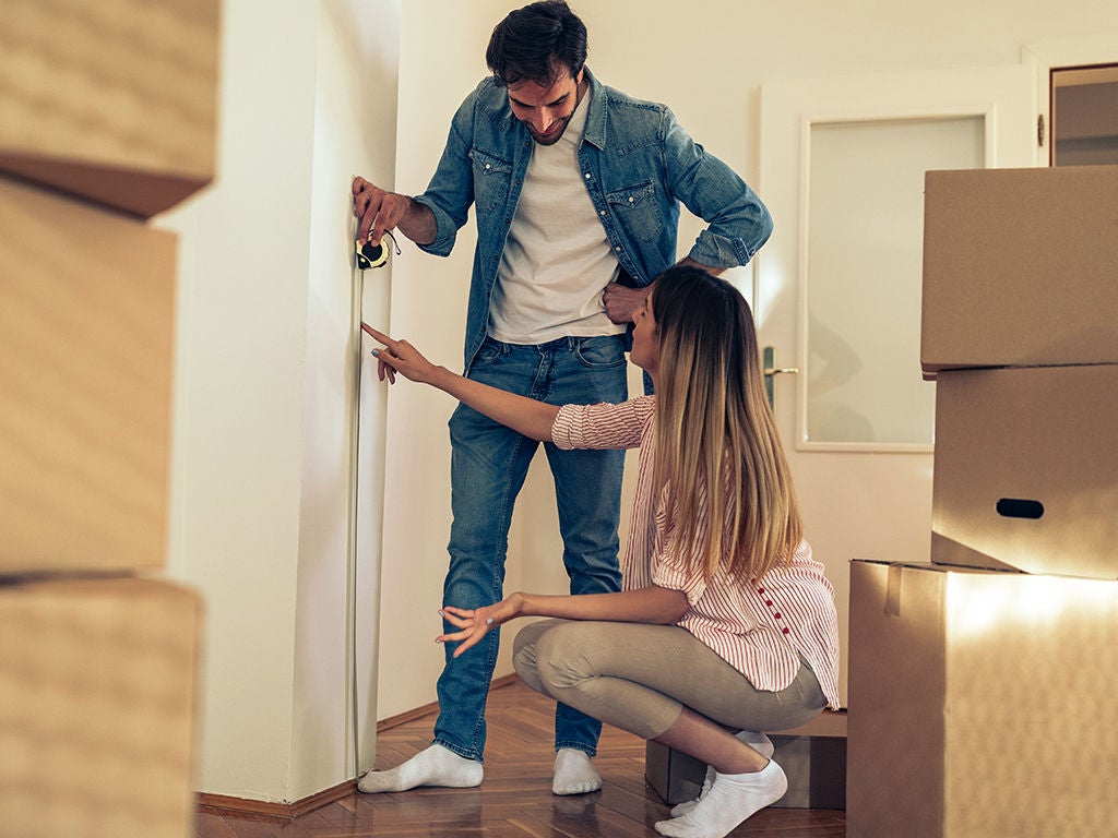 Couple measuring kitchen wall